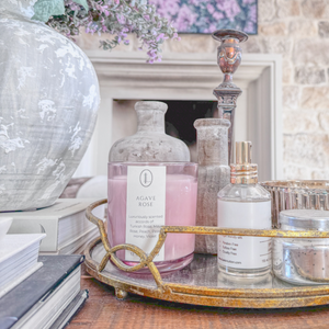 Luxe Intuition Agave Rose candle on a gold-rimmed mirrored tray in a styled vignette