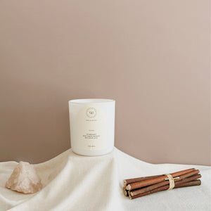 Wick & Bloom 11 11 white candle styled on cream linen with a bundle of wood sticks and natural quartz decor