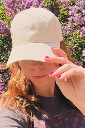 Wick & Bloom "Candle Snob" embroidered cap in cream, worn by a model