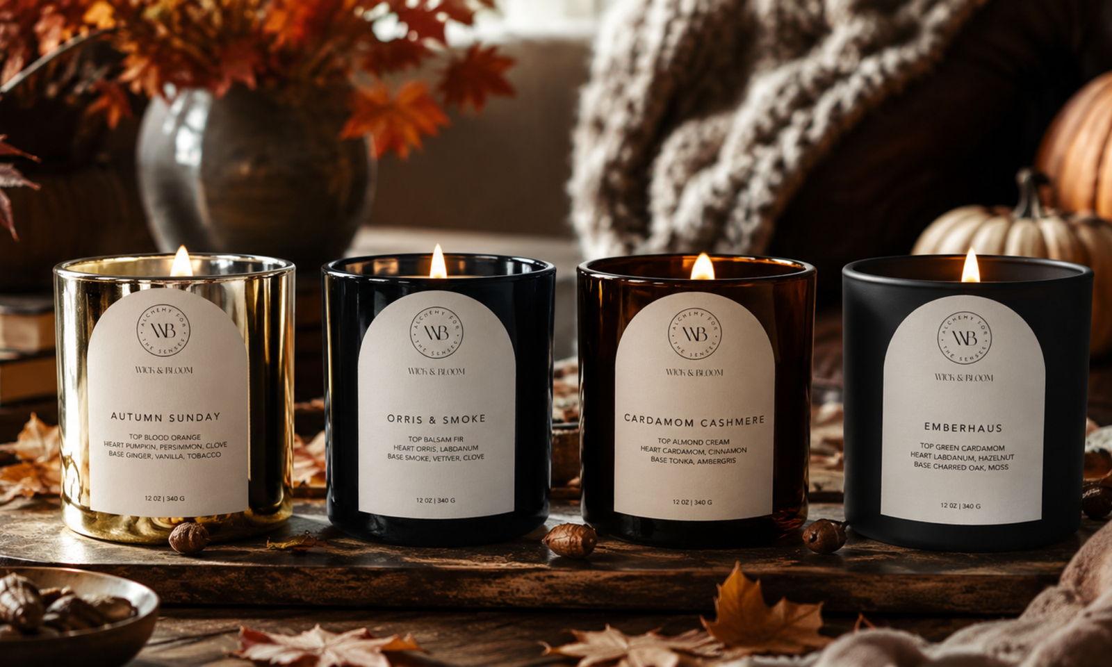 Four Wick & Bloom fall candles lit on a wooden table Autumn Sunday in a gold vessel, Orris & Smoke in black, Cardamom Cashmere in amber glass, and Emberhaus in matte black — surrounded by autumn leaves and a knit throw.