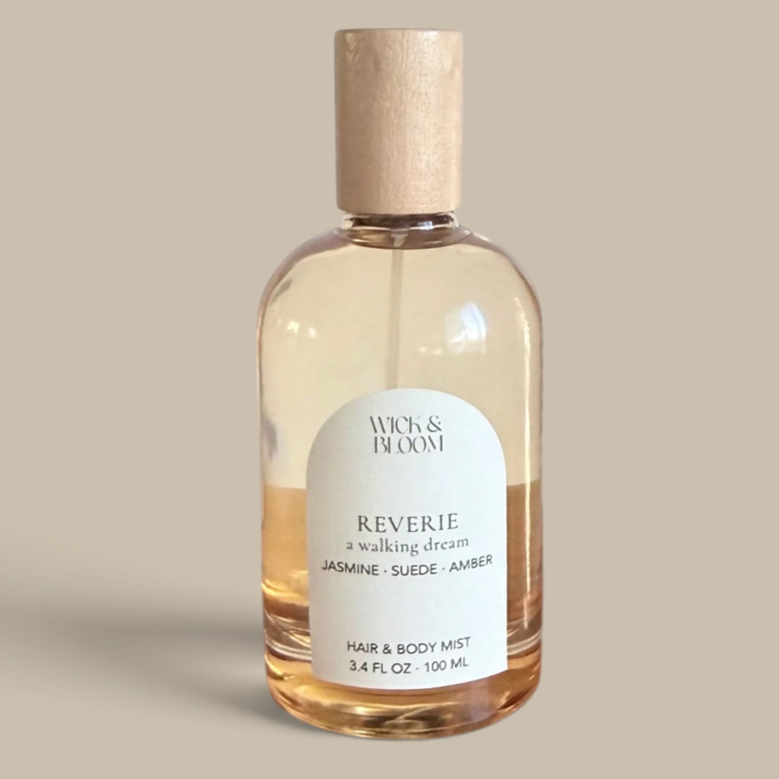 REVERIE Hair & Body Perfume by Wick & Bloom in a 3.4 oz glass bottle with a wooden cap and arched cream label, on a neutral background